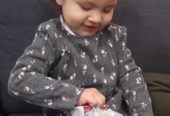 Captura de video del momento en que esta nena abre el regalo que le entregó su papá por Navidad.