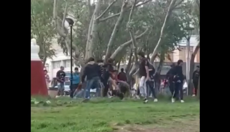 Jóvenes peleando en la plaza.