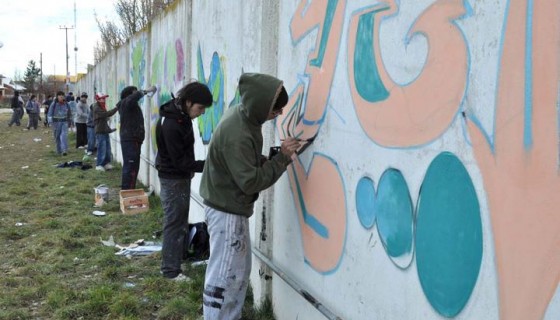 Jovenes realizando grafitis sobre uno de los paredones. 